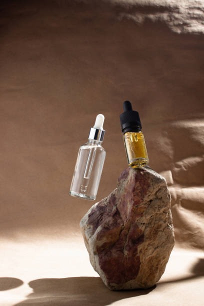 dua-botol-kaca-dengan-serum-transparan-dan-minyak-kuning-melayang-dengan-latar-belakang-krem